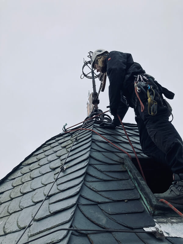 Sichtprüfung der Schieferdeckung auf Kirchendach durch Industriekletterer